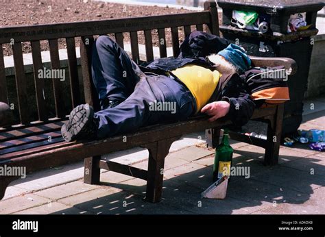 A Tramp Vagrant Or Hobo On A Bench In The Park With A Bottle Of Booze