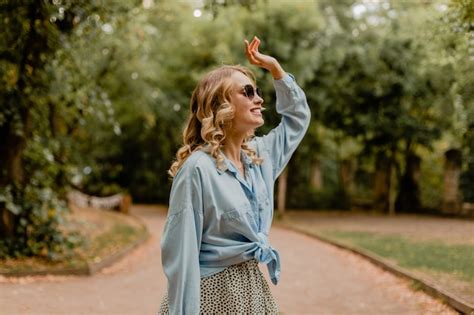 Jolie femme souriante blonde marchant dans le parc en tenue d été Photo Gratuite