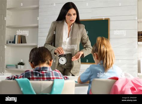 Teacher With Alarm Clock Scolding Pupils For Being Late In Classroom