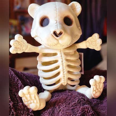 There Is A Fake Skeleton That Looks Like A Bear On Top Of A Purple Blanket