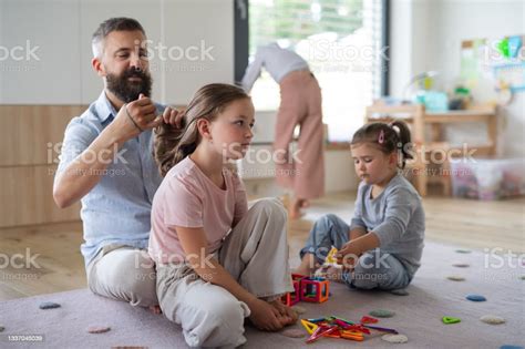 Father With Three Daughters Indoors At Home Playing And Making Hair