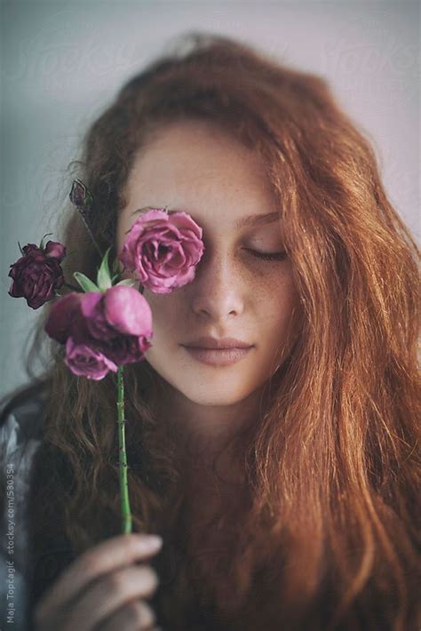 Beautiful Young Redhead With Freckles Covering Her Eye With A Rose By