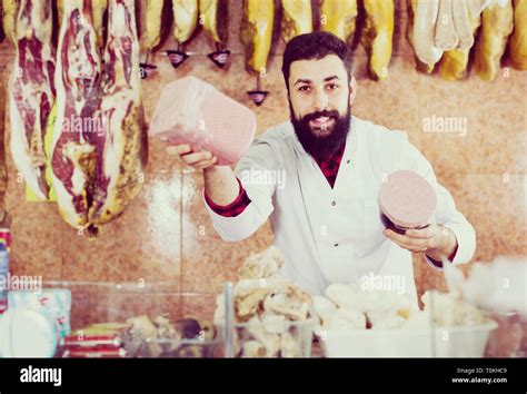 Male Shop Assistant Demonstrating Meatloaf In Butchers Shop Stock