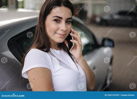 Attractive Young Woman Using Her Phone And Leaned On Her Car At Gas