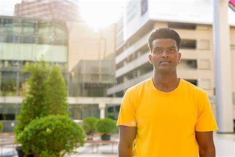 Portrait Of Handsome Black African Man Wearing Yellow T Shirt Outdoors