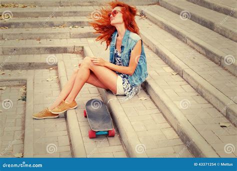 Redhead Women Sitting On A Stairs With Her Skateboard In Sunglasses