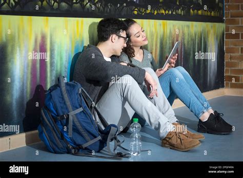 University Students With Digital Tablet In Front Of Graffiti Wall