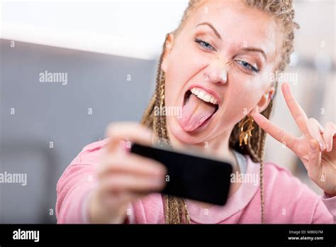 Young Woman Pulling A Goofy Face For A Selfie Sticking Out Her Tongue