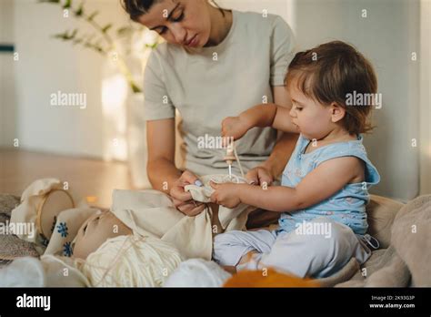 Little baby girl learning to embroider needlework with help of her