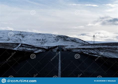 Long Asphalt Road Leading To Snowy Mountains In Iceland Stock Photo