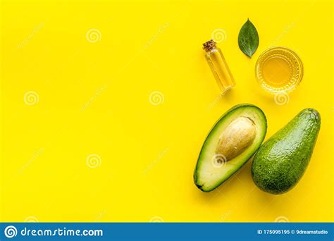 Avocado Oil - for Cooking - in Glass Bowl Near Halfs of Vegetable on Yellow Background Top-down ...