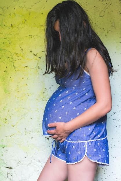 Premium Photo Side View Of Pregnant Woman Standing With Hands On Stomach Against Wall