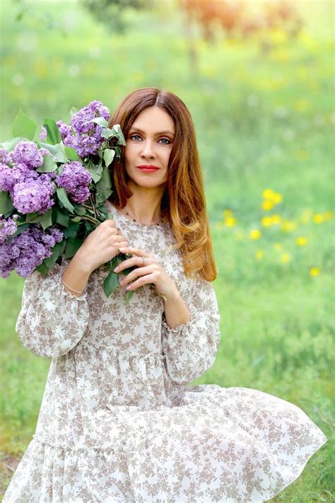 Tender And Romantic Girl In A Summer Dress With A Bouquet Of Lilacs