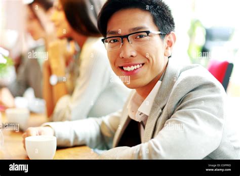 Portrait Of Cheerful Businessman Sitting In Front Of Colleagues Stock