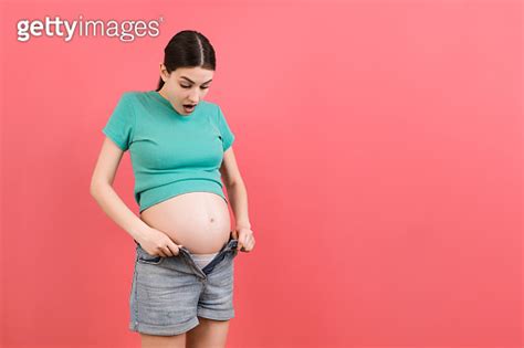 Pregnant Woman In Unzipped Jeans Showing Her Naked Belly At Colorful