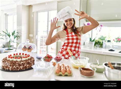 Beautiful Young Brunette Pastry Chef Woman Cooking Pastries At The Kitchen Showing And Pointing