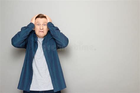 Portrait Of Shocked Mature Man Clutching His Head With Both Hands Stock