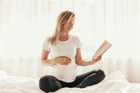 Mujer Embarazada Leyendo Libro En Casa Foto De Archivo Imagen De