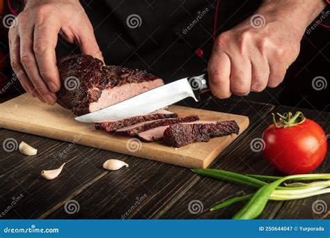 Chef Cuts The Baked Veal Meat On A Cutting Board The Concept Of