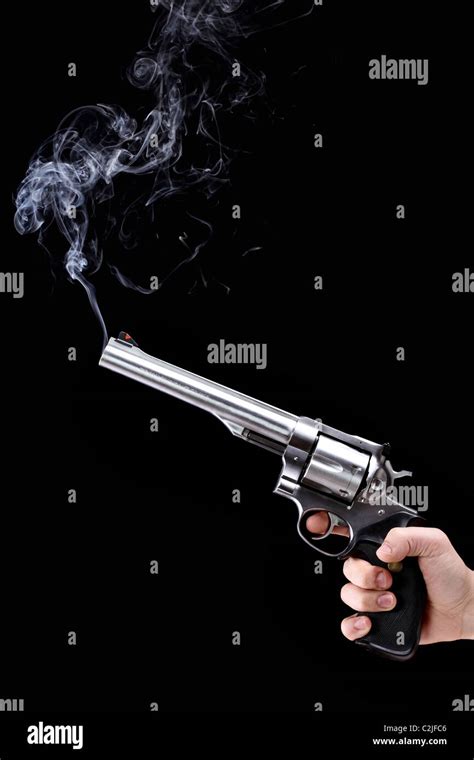 hand holding a revolver with smoking barrel, against black background Stock Photo - Alamy