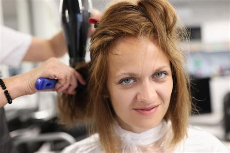 Premium Photo Woman Hairdresser Dries And Straightens Client Hair