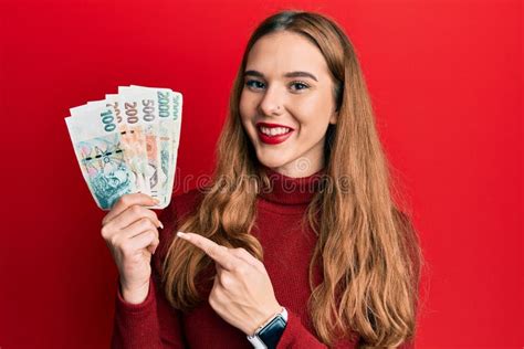 Young Blonde Woman Holding Czech Koruna Banknotes Smiling Happy Pointing With Hand And Finger