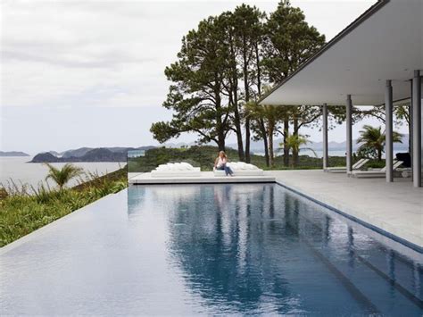 A Woman Sitting On The Edge Of A Swimming Pool Next To A Large Body Of