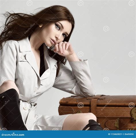 Beautiful Brunette Hipster Woman In Gray Autumn Jacket With Windy Hair Sitting Near Leather