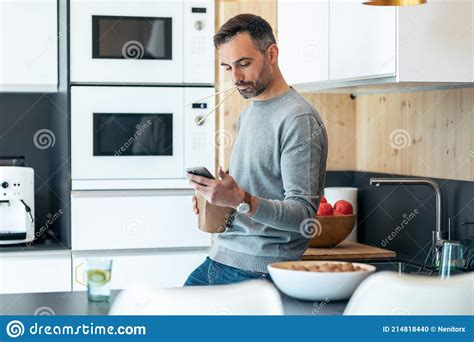 Handsome Mature Business Man Eating Take Away Noodles While Using