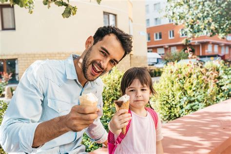 Linda Niña Sentada Con Papá En La Calle De La Ciudad Y Comiendo Helado