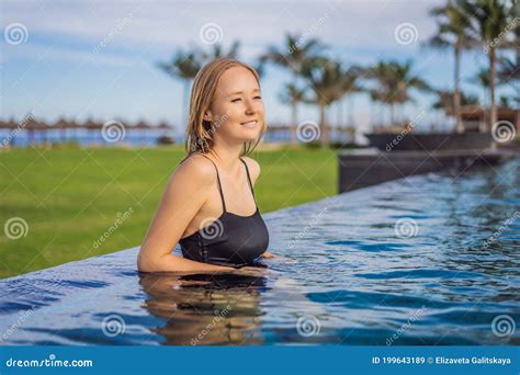 Woman Relaxing In Infinity Swimming Pool Looking At View Stock Image