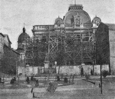 An Old Building With Scaffolding On It S Sides And People Walking Around