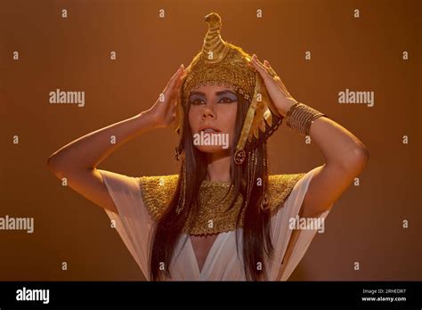 Beautiful Brunette Woman In Egyptian Outfit Touching Headdress In Light