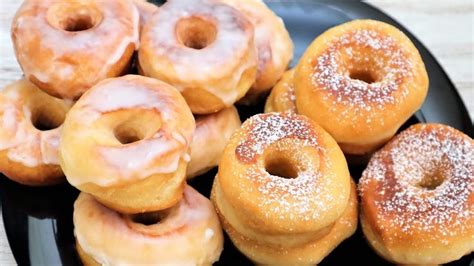 A Black Plate Topped With Donuts Covered In Frosting