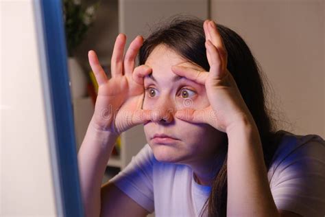 The Woman Forces Herself To Look Into The Computer Screen Opening Her Eyes Wide With Her Hands