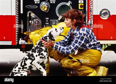 Hispanic Female firefighter pets the firehouse dog Stock Photo - Alamy