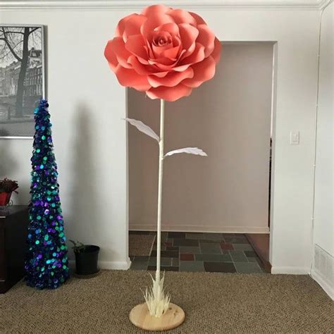 A Large Paper Flower Sitting On Top Of A Wooden Stand Next To A Christmas Tree