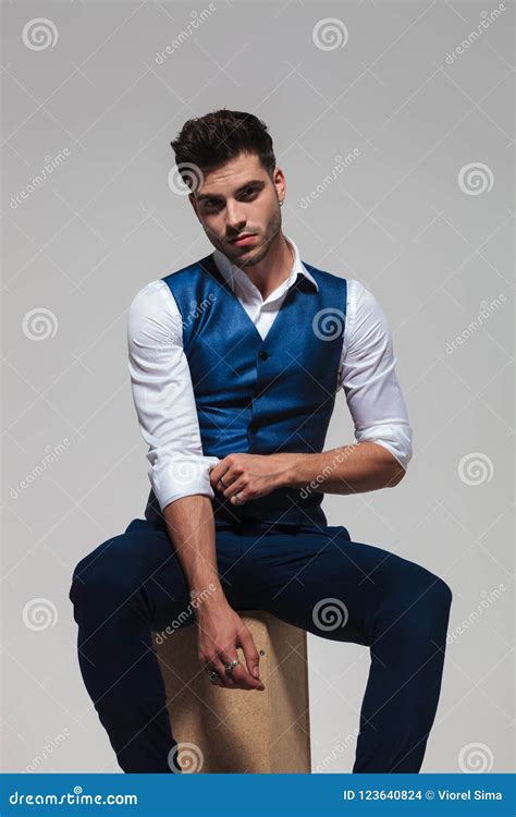 Seated Elegant Man Wearing A Blue Vest Fixes His Sleeves Stock Photo