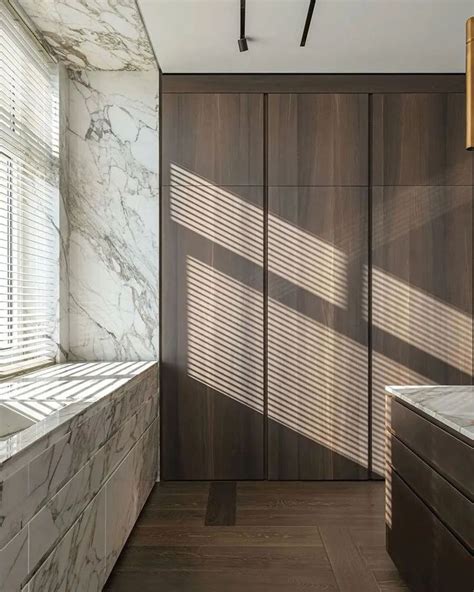 A Bathroom With Marble Walls And Flooring Next To A Window Covered In