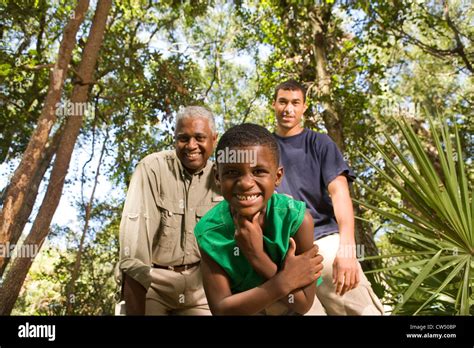 Portrait Of A Mature Man With His Son And Friend Smiling At Forest Stock Photo Alamy