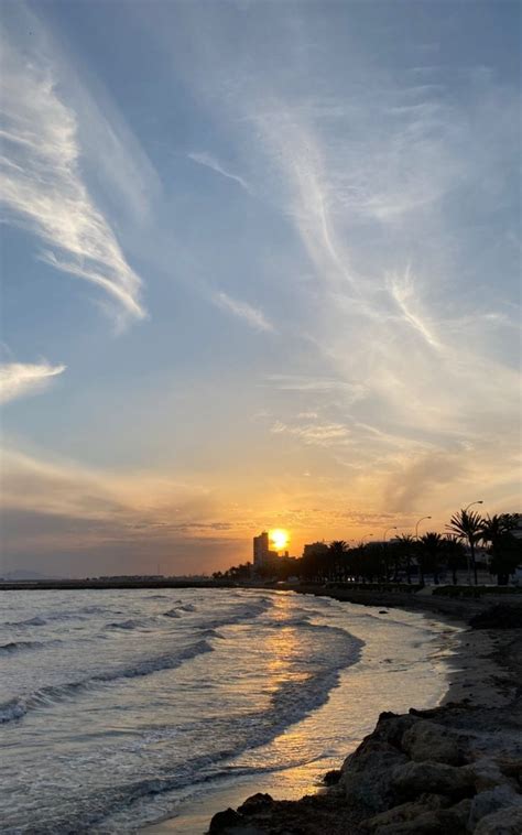 The Sun Is Setting Over The Water At The Beach