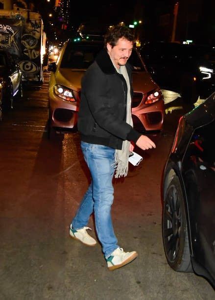 A Man Walking Down The Street Next To Parked Cars