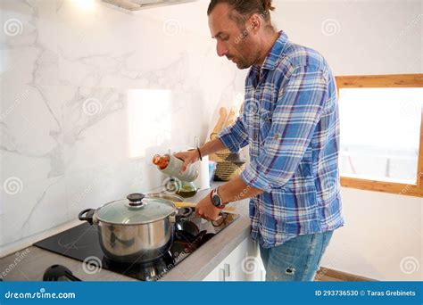 Authentic Portrait Of A Young Adult Handsome Man Cooking At Home Stock