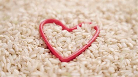 Unprocessed Integral Brown Rice Seeds Falling On A Full Red Heart Shape