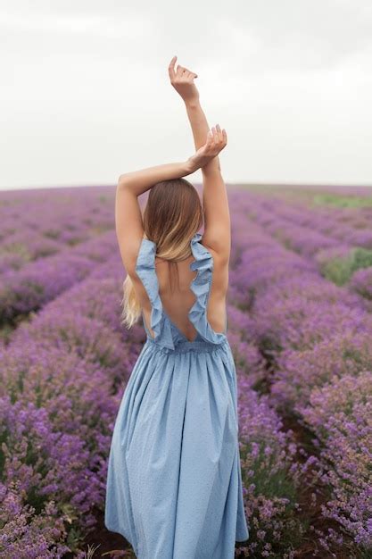 Jeune femme blonde souriante aux cheveux longs vêtue d une robe bleue sur le champ de lavande