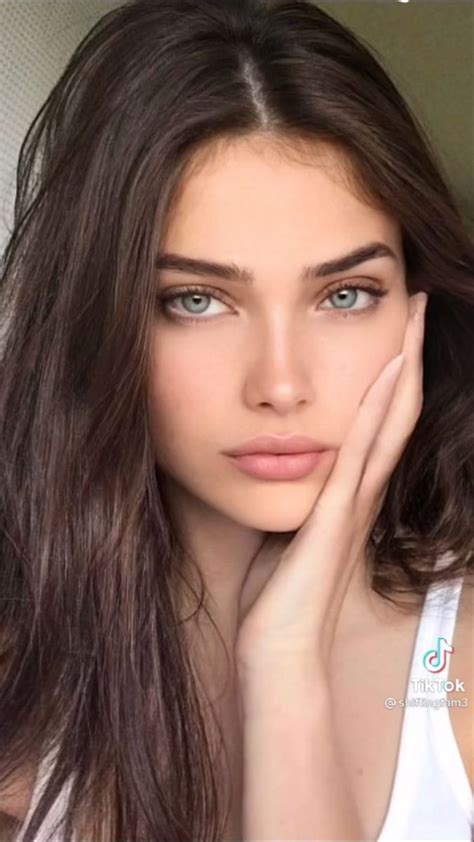 A Woman With Long Brown Hair And Blue Eyes Is Posing For The Camera