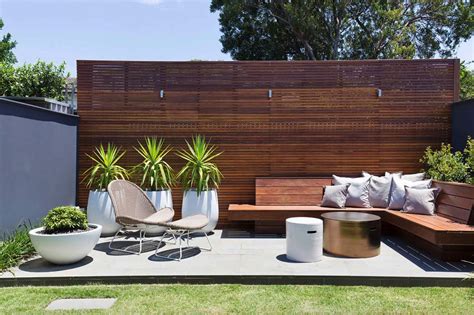 an outdoor seating area with potted plants and wooden slatted fence in ...