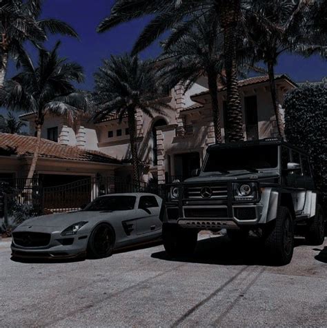 Two Mercedes Benzs Parked In Front Of A House With Palm Trees On The Street