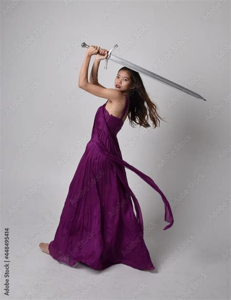 Full Length Portrait Of Pretty Brunette Asian Girl Wearing Purple Flowing Gown Sitting Pose