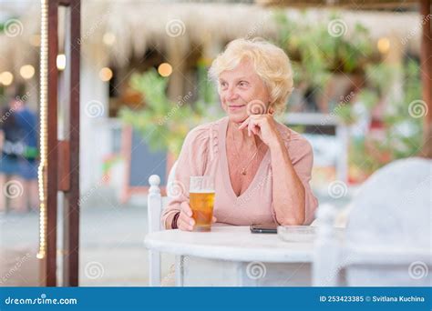Mature Woman Sitting At A Table In A Summer Cafe And Drinking Beer Stock Image Image Of Female